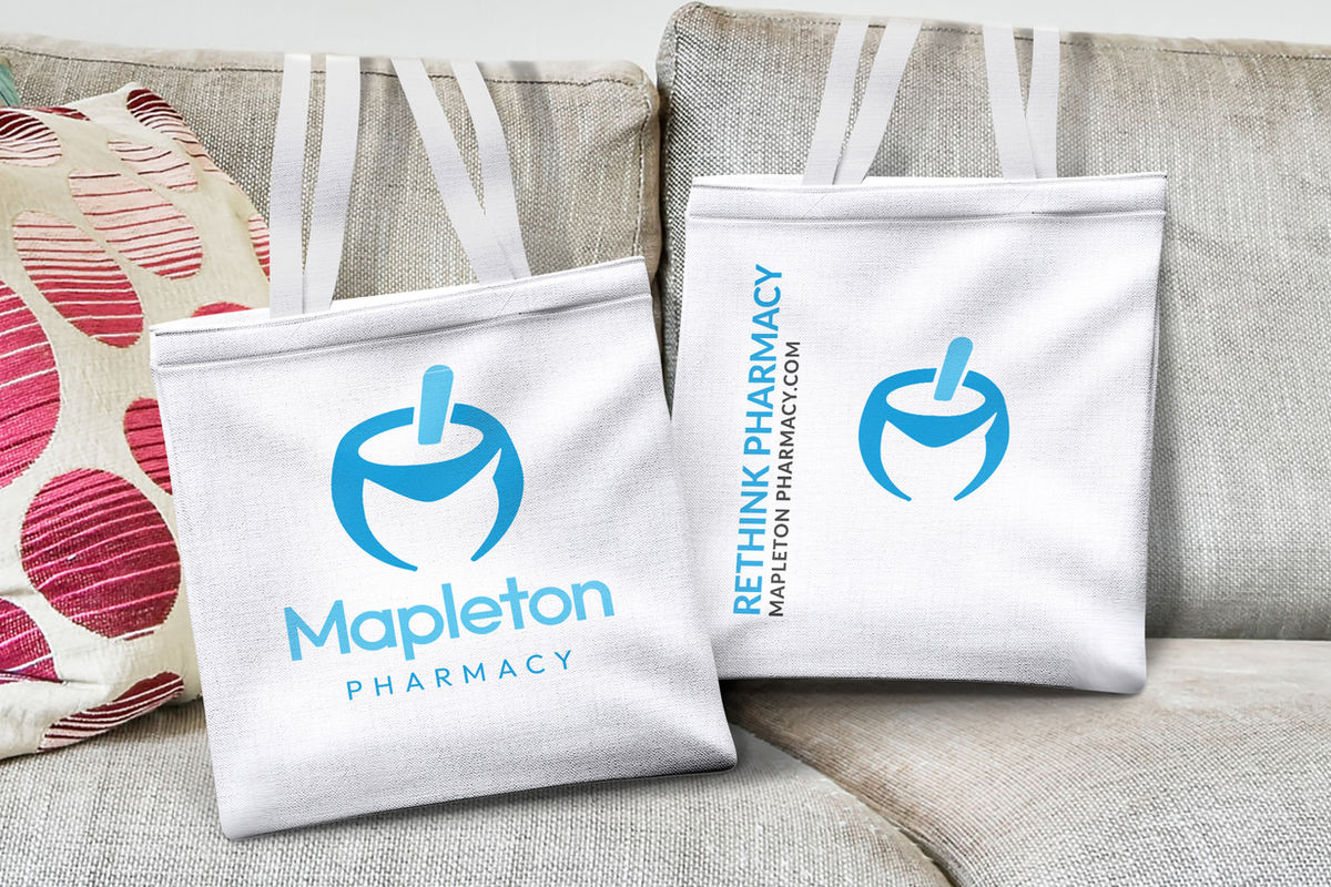 Mapleton Pharmacy branded packaging and totes styled on a couch